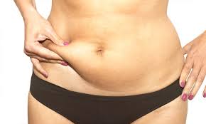 mulher+40 acumula gordura abdominal comprime uma dobra de gordura de seu abdômen.